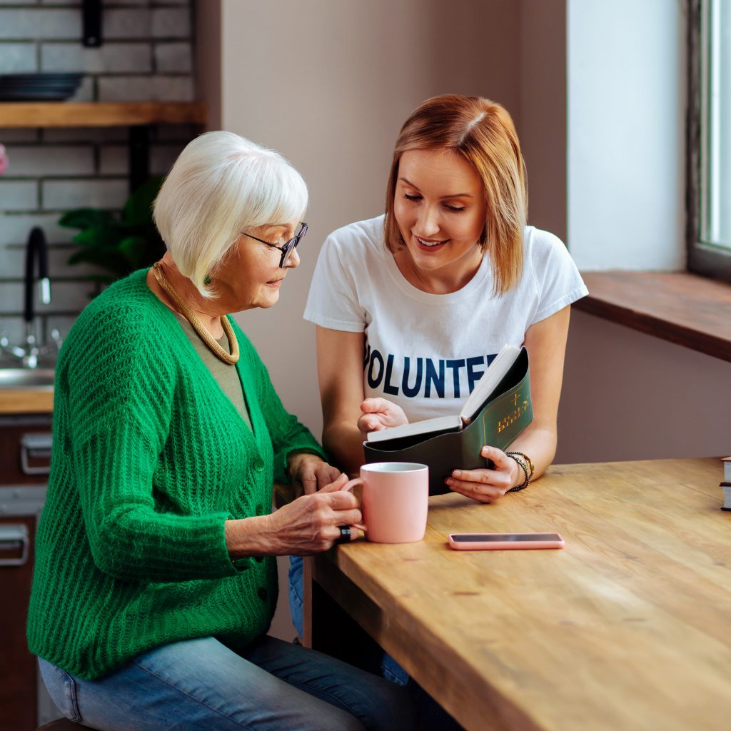 Eine Betreuerin und ältere Frau sitzen an einem Tisch und unterhalten sich