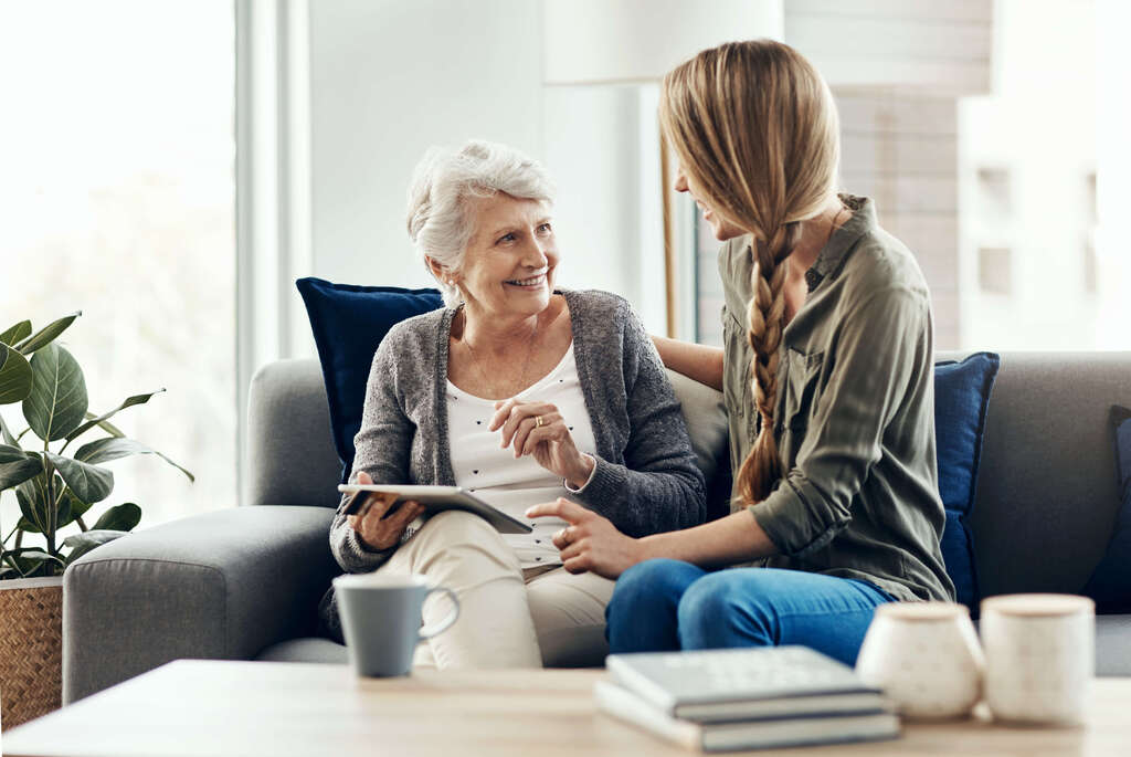Beratungsgespräch zwischen Pflegekraft und Seniorin zur Betreuung zuhause